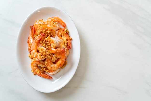 fried shrimps or prawns with garlic on white plate - seafood style