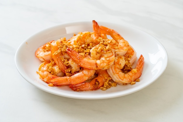 fried shrimps or prawns with garlic on white plate - seafood style