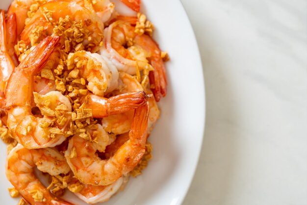 fried shrimps or prawns with garlic on white plate - seafood style