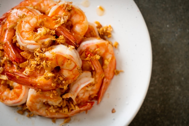 fried shrimps or prawns with garlic on white plate - seafood style