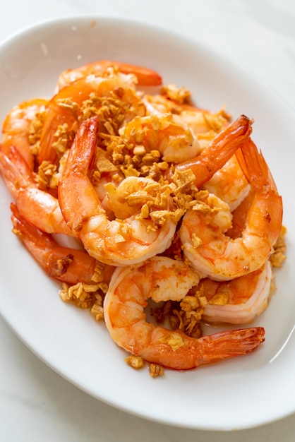 fried shrimps or prawns with garlic on white plate - seafood style