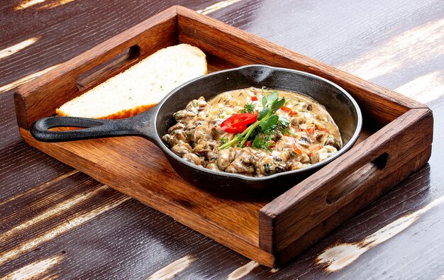 Fried snails in cream sauce in a cast iron pan On a wooden stand