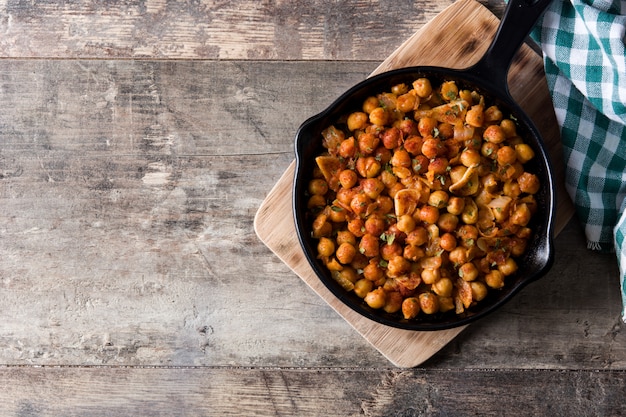 Fried spicy chickpeas in frying pan on wooden table Top view copy space