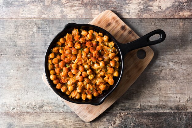 Fried spicy chickpeas in frying pan on wooden table Top view