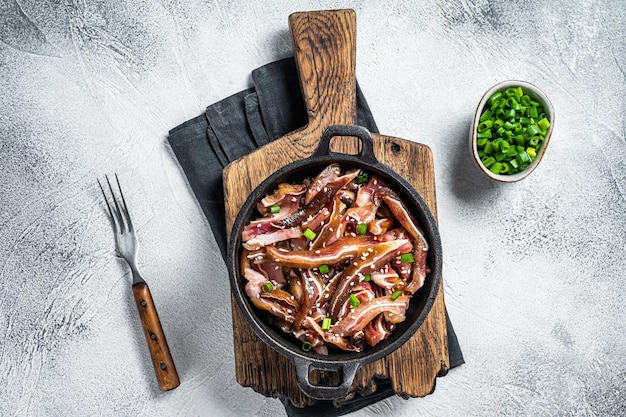 Fried spicy pork pig ears served in a frying pan white background Top view