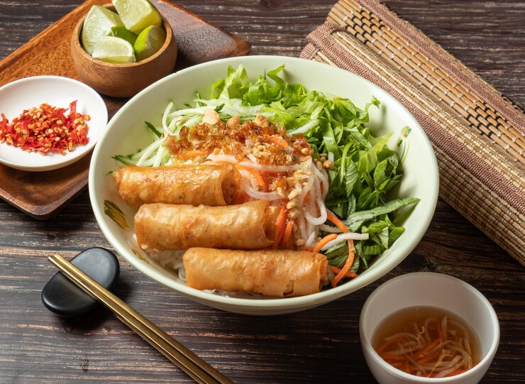台湾料理のテーブル トップ ビューで分離されたボウルにソースを添えた揚げ春巻き冷たい米春雨