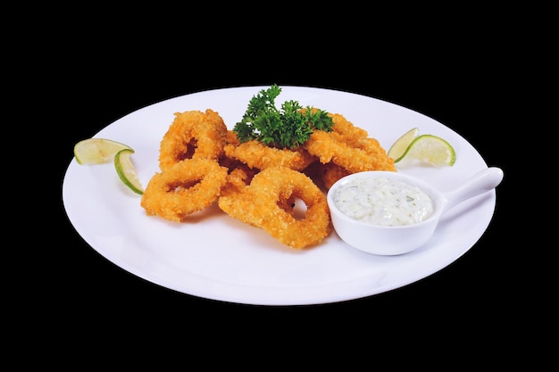 Fried squid or octopus calamari with sauce isolated against a background of dark