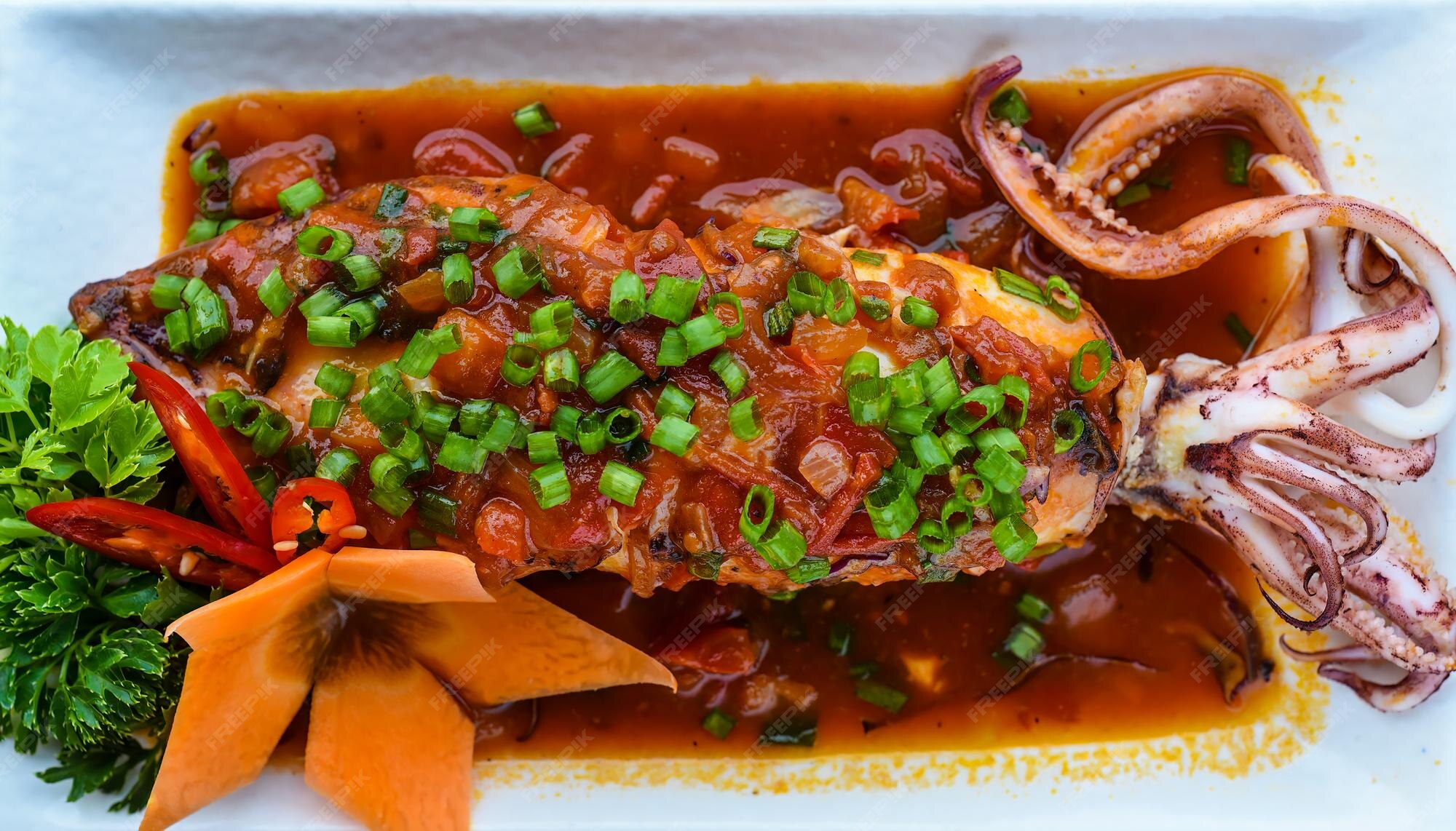 Premium Photo | Fried squid in red sauce on black background for a menu