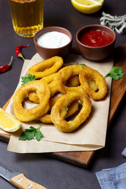 Fried squid rings with two sauces, lemon and herbs. Fast food. Appetizer.