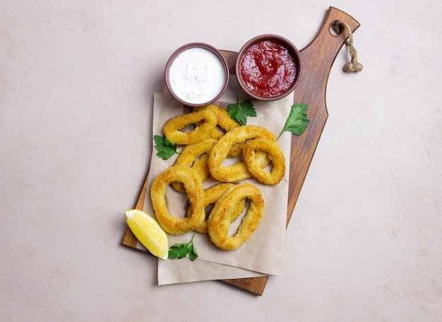 Fried squid rings with two sauces, lemon and herbs. Fast food. Appetizer.