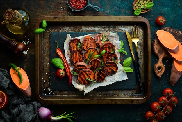 Patate dolci fritte con paprika al rosmarino e peperoncino su una lastra di pietra nera vista dall'alto spazio libero per il testo