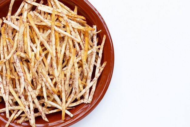 Fried taro sticks in bowl on white background.