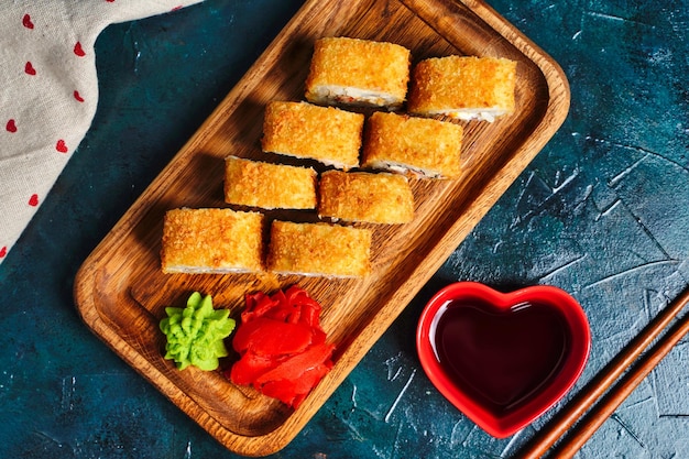 Fried tempura sushi rolls set on wooden plate on dark background Japanese traditional fusion food style Top view High quality photo