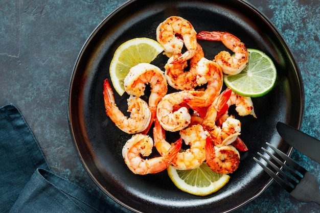 Fried tiger shrimp with lime lemon and spices on a black plate Healthy dinner or lunch concept