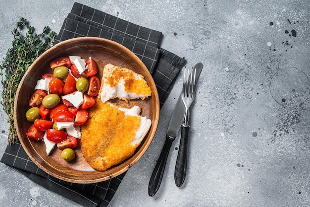 Fried tilapia fillet on a plate with salad Gray background Top view Copy space