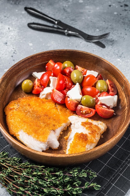 Fried tilapia fillet on a plate with salad Gray background Top view