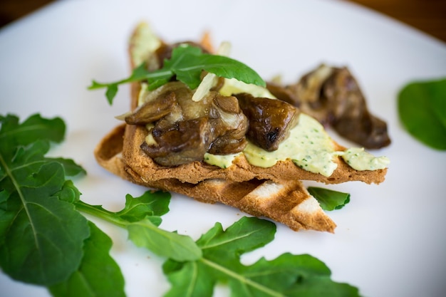 fried toast with cheese spread arugula and fried mushrooms in a plate