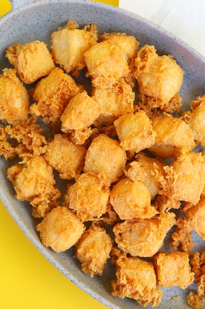 Photo fried tofu on the newspaper and yellow background  portrait view