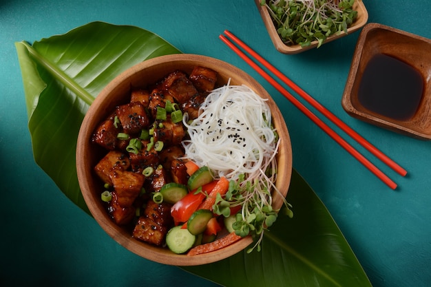 Fried tofu with rice crystal noodles in a wooden bowl.