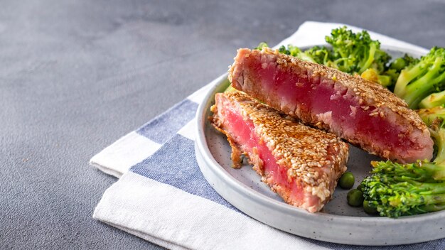 Fried tuna with broccoli and green peas on a plate.