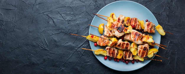 Fried turkey meat with apple on wooden skewers.Appetizing barbecue.Space for text