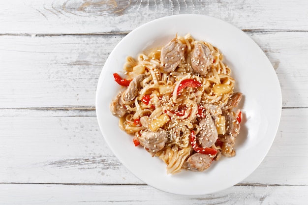 Fried udon noodles with pork and pineapple on wooden table. Pad thai