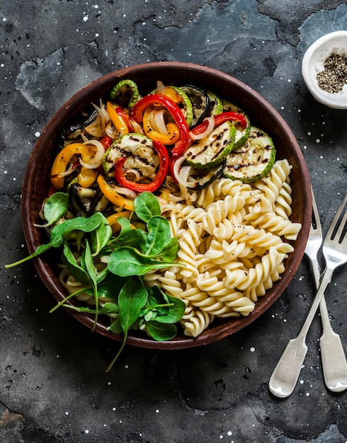 Fried vegetables and fusilli pasta antipasti salad on dark background top view