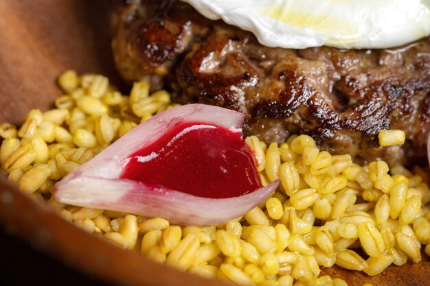 Fried venison steak with poached egg and boiled barley Black isolated background Side view macro