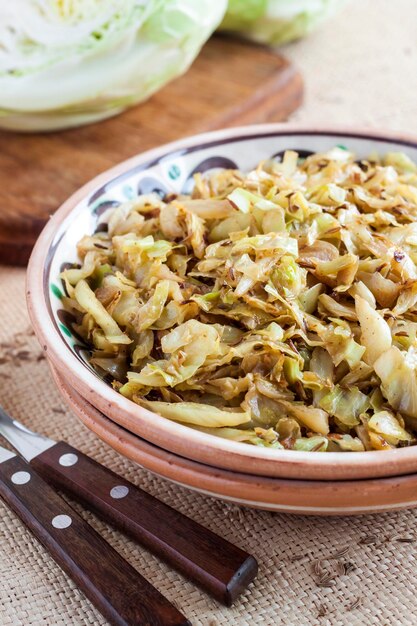 Fried white cabbage with caraway seeds and curry powder on rustic plate