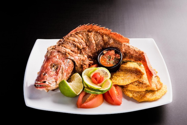 Fried whole red snapper  with fried plantain and lemon with tomato