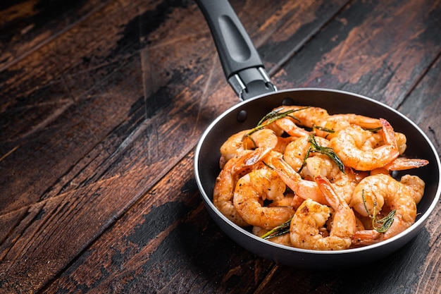 Fried with butter and garlic prawns shrimps in a skillet Wooden background Top view Copy space