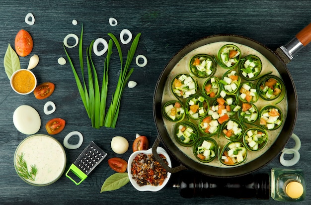 Fried young sliced courgettes in a pan on a dark surface