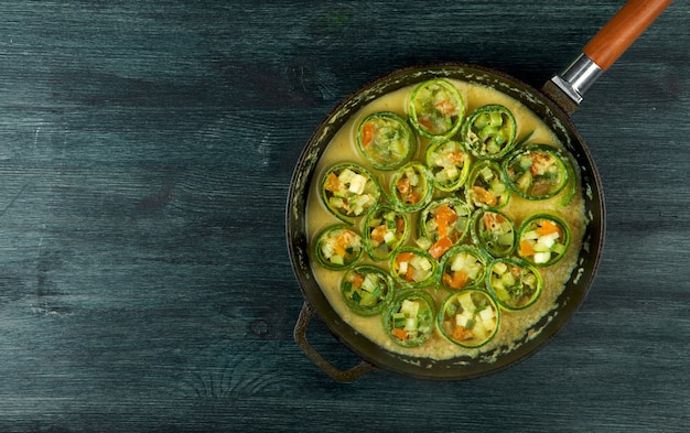 Fried young sliced courgettes in a pan on a dark surface