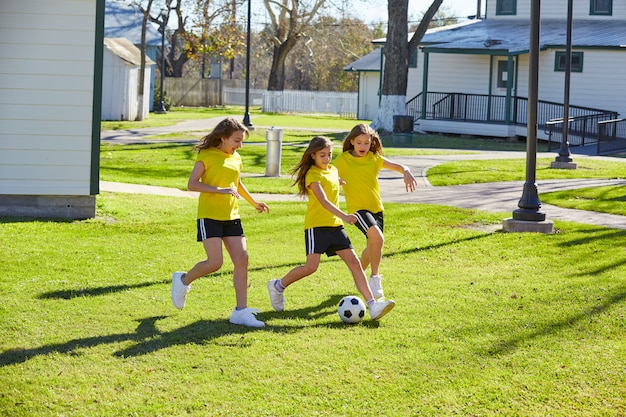 Amici ragazze adolescenti che giocano a calcio in un parco