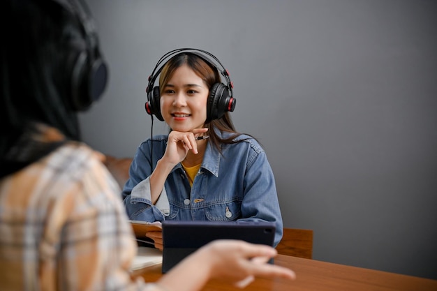 친절한 아시아 여성과 그녀의 친구가 스튜디오에서 함께 온라인 팟캐스트를 운영하고 있습니다.