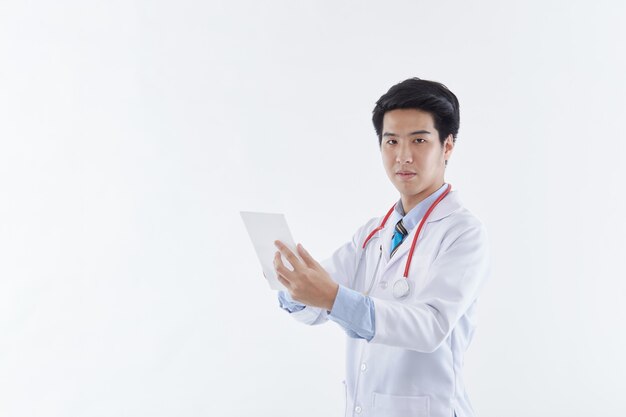 A friendly Asian male doctor in a white coat and red stethoscope using a tablet