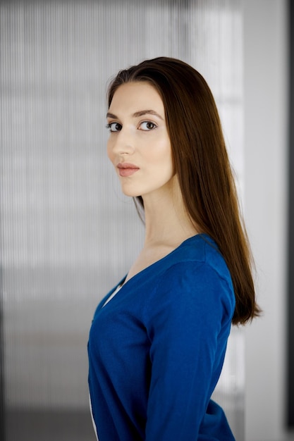 Friendly asian student girl standing straight. Business headshot or portrait in office.