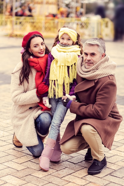 Friendly atmosphere. Beautiful girl looking straight at camera while caressing her parents