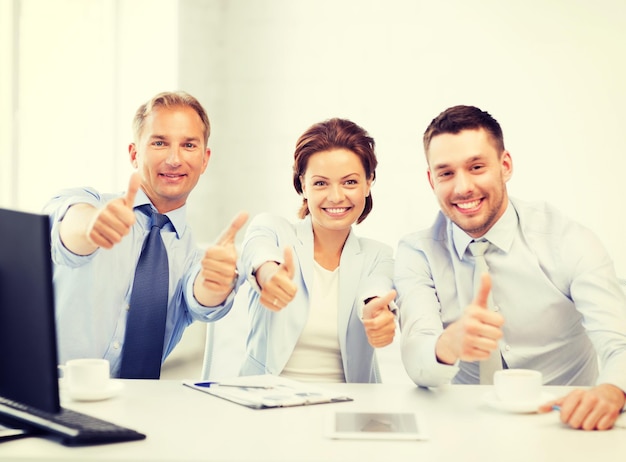 Дружелюбная бизнес-команда показывает большие пальцы в офисе