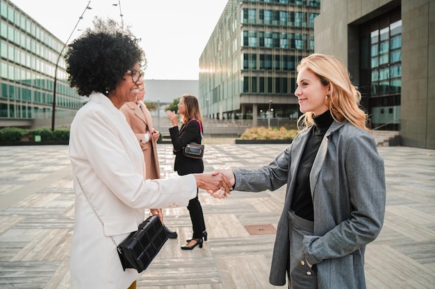 Friendly businesswoman greeting and handshake of new staff member young female business people on