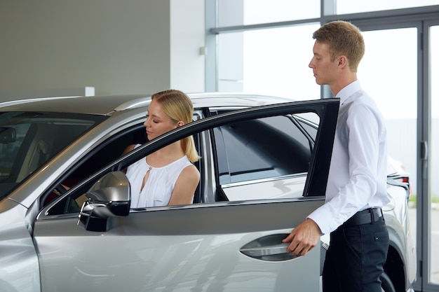 A friendly car dealer explains the pros and cons of a new car at the dealership