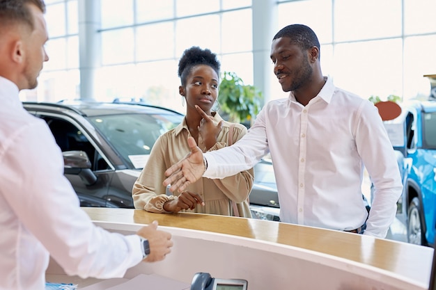 friendly caucasian manager greeting customers in car salon