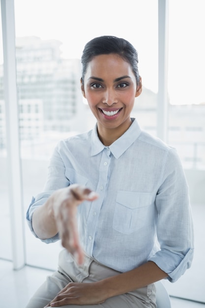 Friendly chic businesswoman reaching her hand