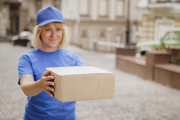 Donna di consegna amichevole in uniforme blu sulla strada della città