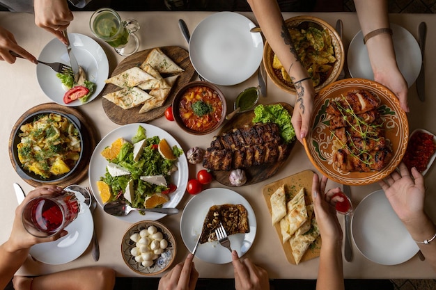 Friendly dinner Top view of group of people having dinner together while sitting at the rustic wooden table with many plate of delicious and satisfying meals