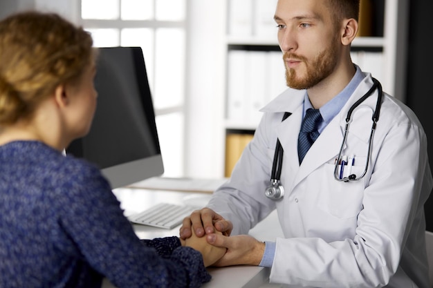 Friendly doctor reassuring his female patient. Medical ethics and trust concept, medicine theme