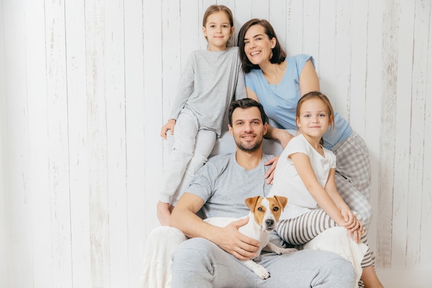 Photo friendly family pose together against white : two little sisters, father, mother and their pet