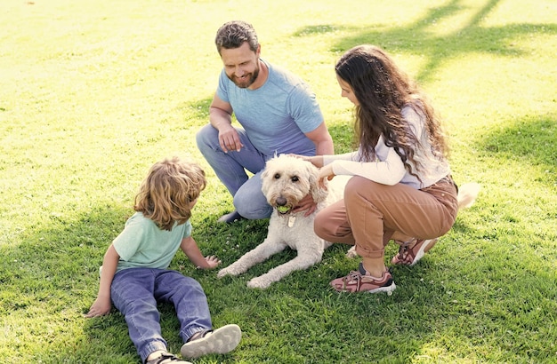 Friendly family with pet happy parents with kid boy play with dog