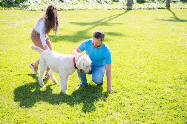 Friendly family with pet having fun. happy man and woman play with dog. guy and girl relax together