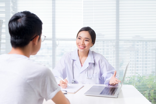 Friendly female doctor hands holding patient hand sitting at the desk